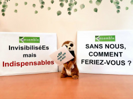 Le suricate tiens un panneau reprenant le hastag Qui prend soin de nous. Il est entouré de deux panneaux : InvisibiliséEs mais indispensables et Sans 