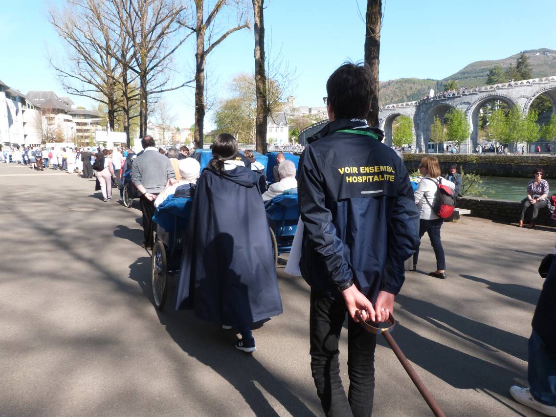 Photo des Hospitaliers dans les sanctuaires de Lourdes en train d'accompagner les pèlerins le long du gave de Pau